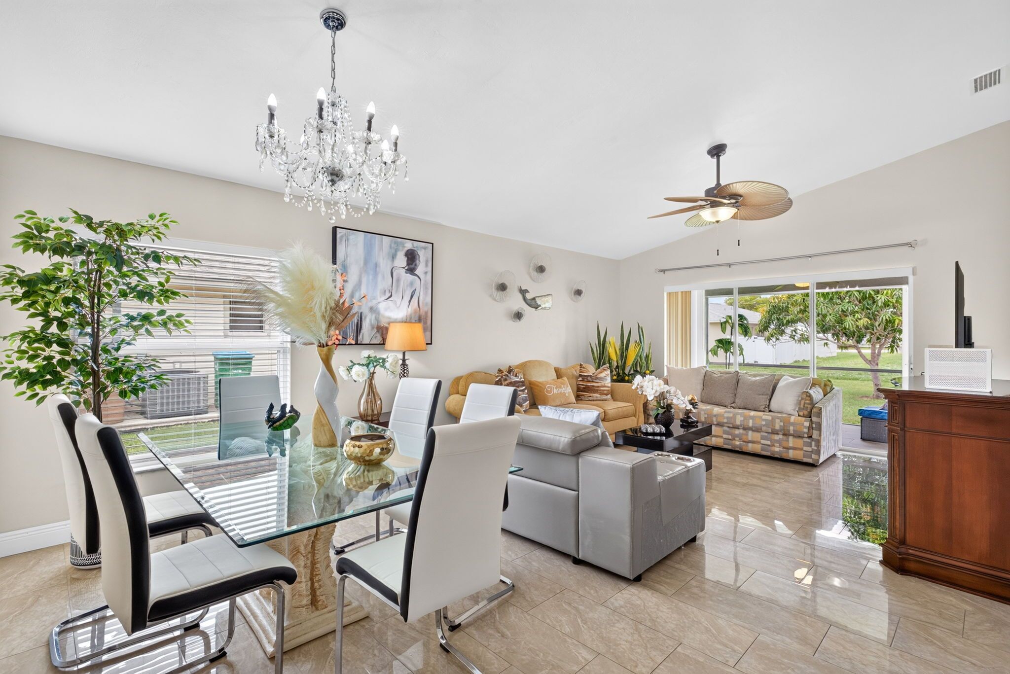 A spacious living area with a dining table, sofas, and a chandelier.