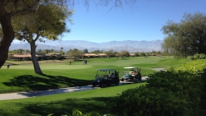 A golf course with a clear view of the mountains in the background, a well-maintained lawn, and a golf cart parked on the side. - Westin Mission Hills (Rancho Mirage)