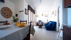 A dining area with a table set for four, a blue sofa, and a small table with a lamp.