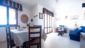 A dining area with a table set for two, a blue sofa, and a television in the background.