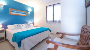 A bedroom with a bed, a nightstand, a chair, a window, and a wall with a painting.
