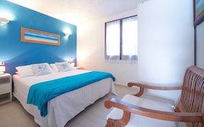 Quarto com cama, mesa de cabeceira, cadeira, janela e parede com uma pintura.
