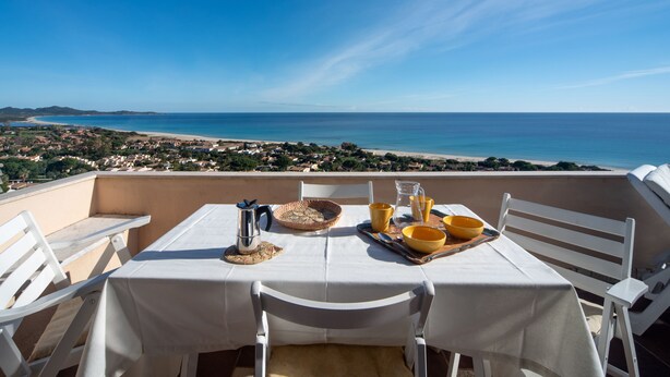 A table set for two with a view of the sea and a coastal town.