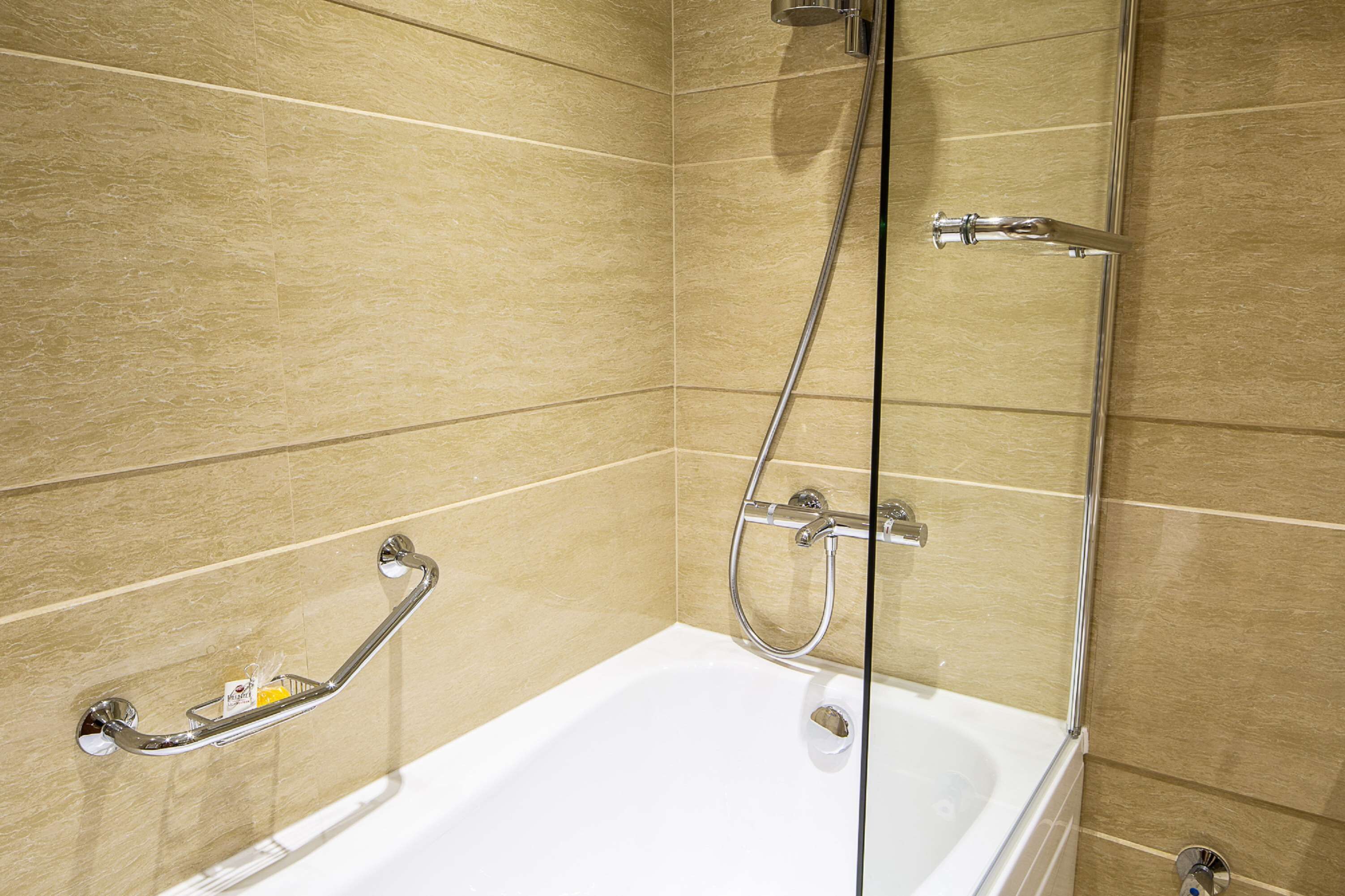 A modern bathroom with a bathtub, a shower, and a grab bar.