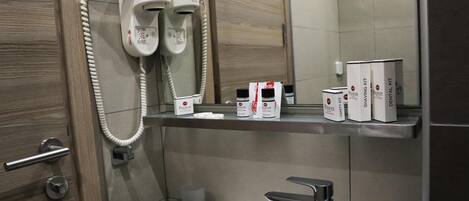 A bathroom with a vanity, a hairdryer, and a shelf with toiletries.