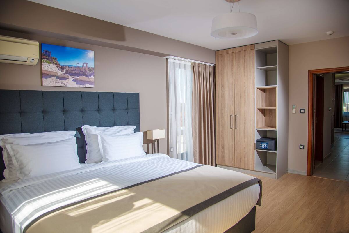 Een hotelkamer met een groot bed, een garderobe, een inbouwkast en een schilderij aan de muur.