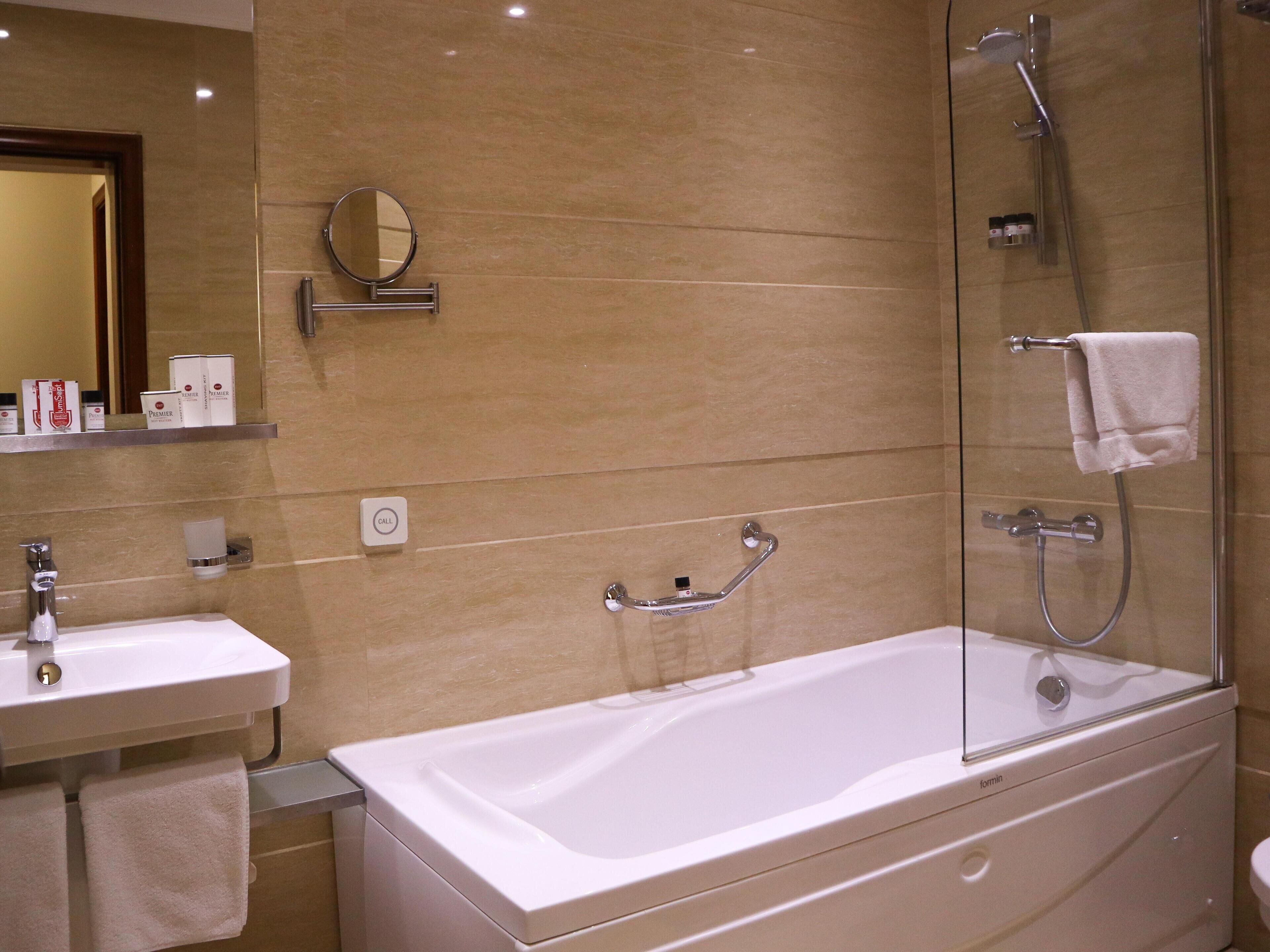 Ein modernes Badezimmer mit einer Dusche in Glasabtrennung, einer weißen Badewanne, einem Waschbecken und einem Spiegel.