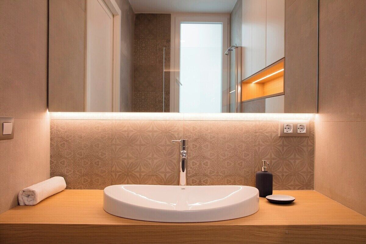 A modern bathroom with a round white sink, a mirror above it, and a towel on the side.