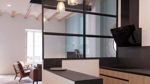 A modern kitchen with a black countertop, wooden cabinets, and pendant lighting.