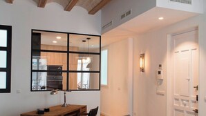 A modern living room with a grey sofa, wooden coffee table, and a dining area with a wooden table and chairs.