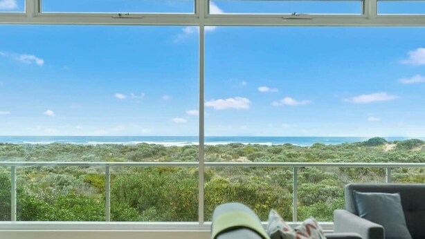 Una habitación con un amplio ventanal que ofrece vistas al océano y abundante vegetación.