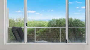 Una ventana con vista a un balcón, barandilla y follaje.