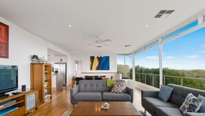Una sala de estar moderna con sofá, mesa de centro, televisor y un ventanal con vistas.