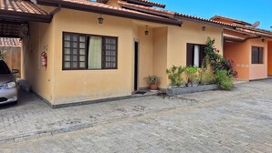 A two-story building with a tiled roof, a fire extinguisher, and a satellite dish. - House in a gated community in São Francisco da Praia, São Sebastião/SP (Praia de São Francisco, São Sebastião)