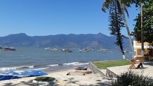 A coastal view with boats on the water and mountains in the background. - House in a gated community in São Francisco da Praia, São Sebastião/SP (Praia de São Francisco, São Sebastião)