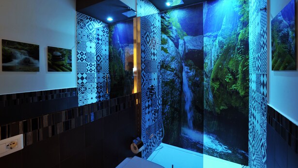Ein Badezimmer mit einem Wasserfall-Wandbild, gemusterten Fliesen und modernem Design.