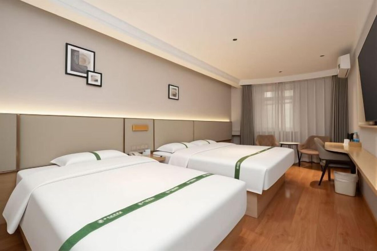 Une chambre d’hôtel avec deux lits, un bureau, une chaise et un téléviseur.