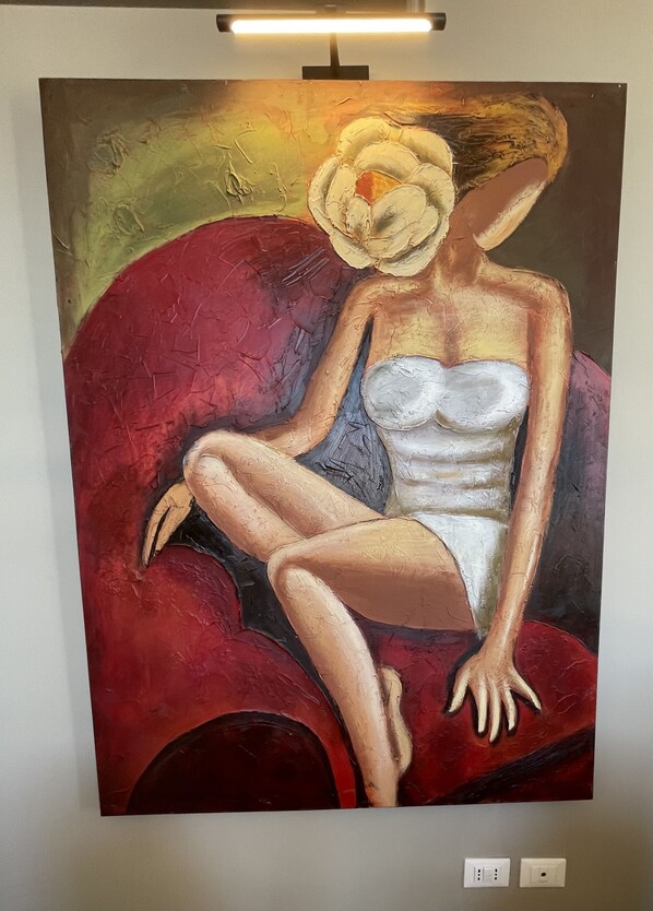 A painting of a seated woman with a flower in her hair, displayed on a wall.