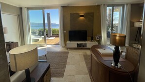 Ein modernes Wohnzimmer mit Fernseher, Lampe und Blick ins Freie.