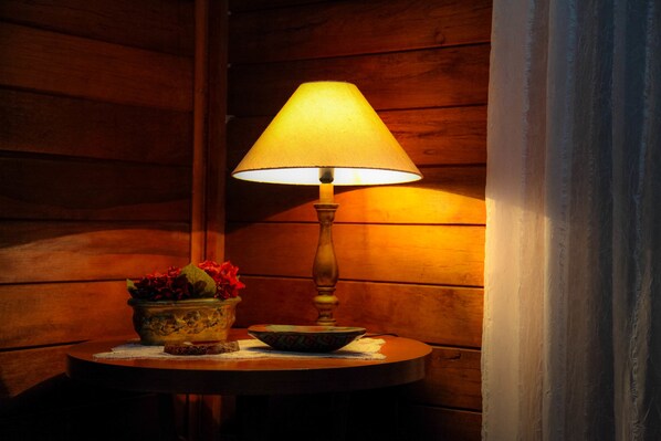 A wooden interior with a table lamp, a bowl, and a vase with flowers. - Fogo Eterno - Pousada de Altitude (Urubici)