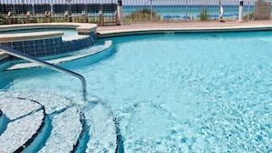 A swimming pool with a clear blue water feature, a poolside area with umbrellas, and a view of the ocean. - 100% Gulf Views ~ Free Beach Chair Service!   (panama city beach)