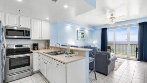 A modern kitchen with white cabinets, stainless steel appliances, and a view to the outside.