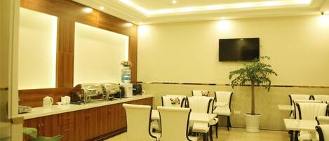 A hotel lobby with a reception desk, seating area, and a television mounted on the wall.