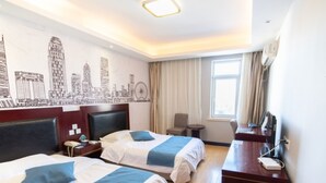 A hotel room with two beds, a desk, a chair, a small table, a window with curtains, and a cityscape mural on the wall. - GreenTree Inn Tianjin Hebei District Beining Park Hotel (Tianjin)