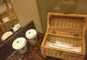 A wicker basket on a countertop next to a mirror, with two containers and a tissue box.