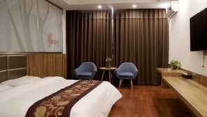 A hotel room with a bed, two chairs, a small table, a TV, and a painting on the wall. - GreenTree Inn TianJin Jinnan District Xiaozhan Training Park Express Hotel (Tianjin)