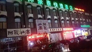 A hotel with a green sign, multiple windows, and a parking lot with cars. - GreenTree Inn TianJin Jinnan District Xiaozhan Training Park Express Hotel (Tianjin)