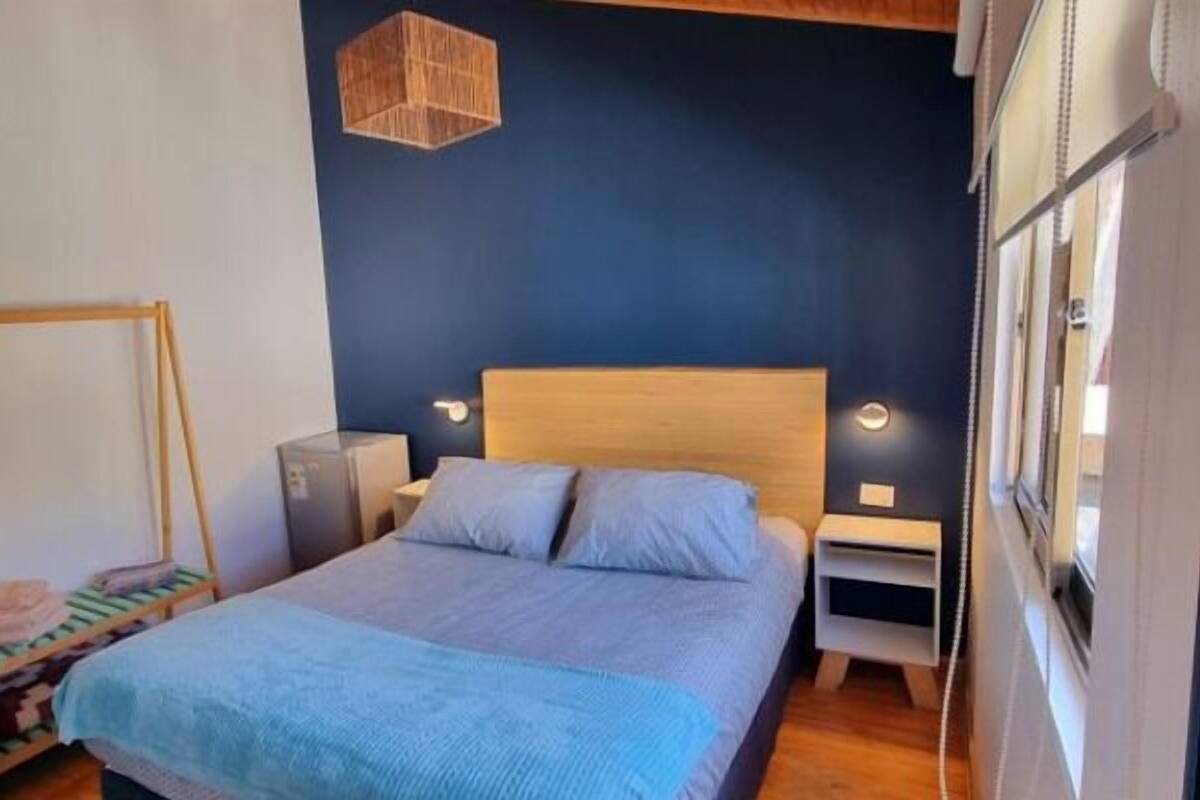 Un dormitorio con cama, mesitas de noche, lámpara colgante y armario.