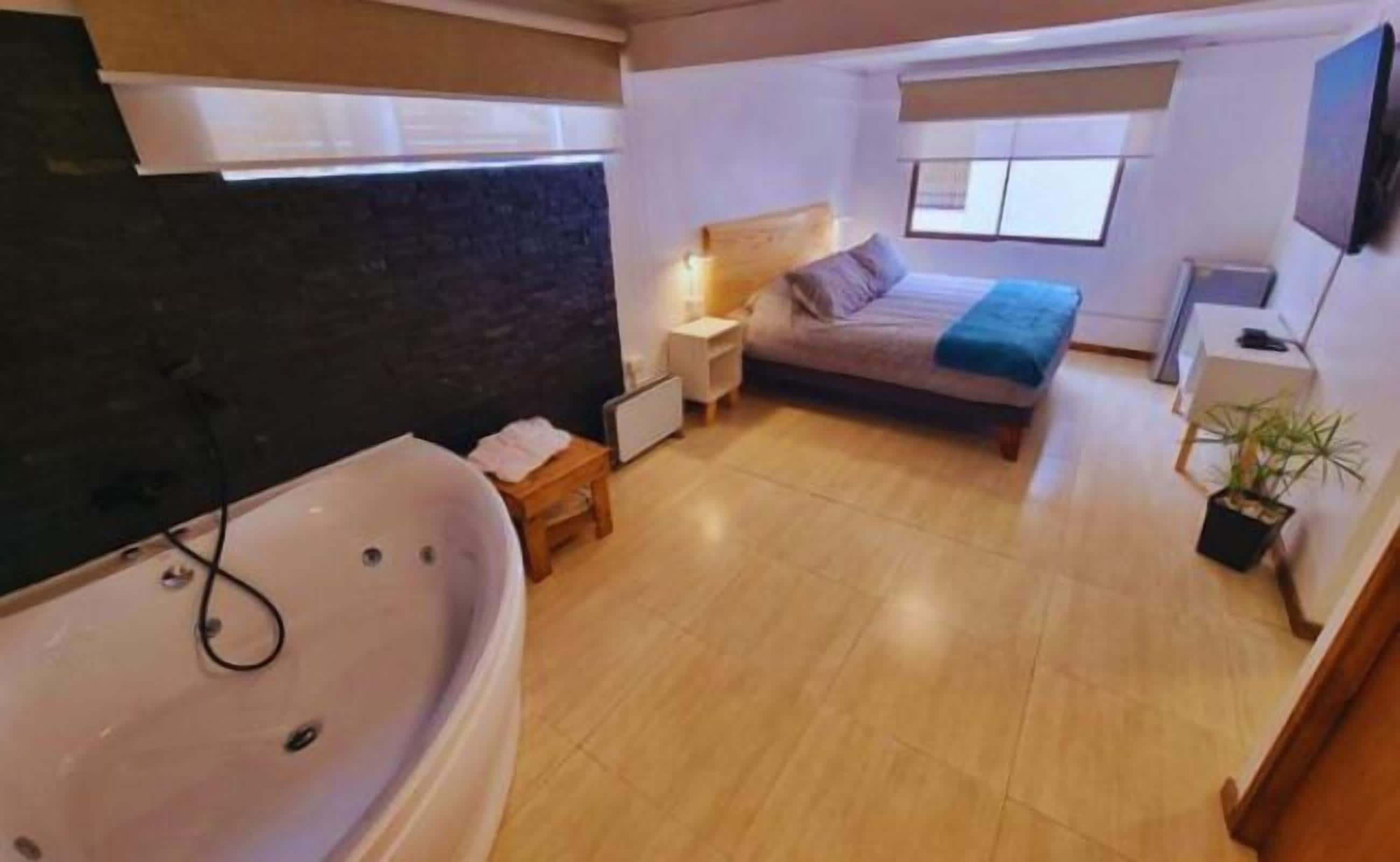 Un dormitorio con cama, mesita de noche, lámpara y ventana.