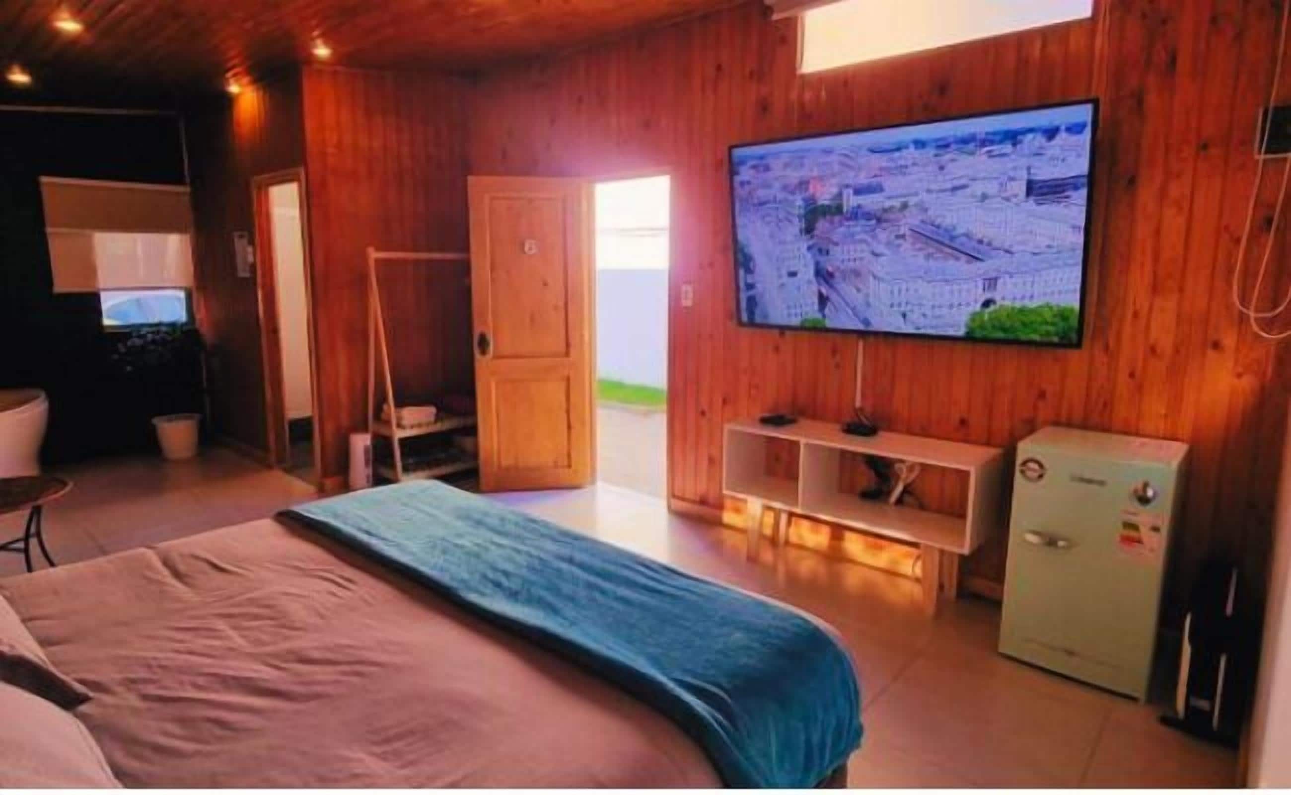 A room with a bed, a television mounted on the wall, and a small cabinet.