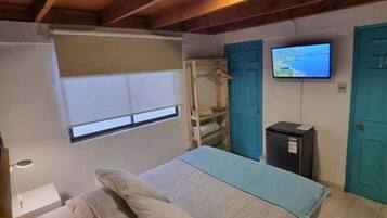 Een slaapkamer met een bed, een televisie, een kledingkast en een klein kastje.