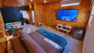 Una habitación con una cama, televisión, escritorio y una silla.