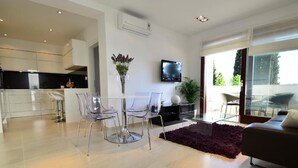 A modern living space with a dining area, a sofa, a TV, and a kitchen in the background. - Villa King (Dubrovnik)