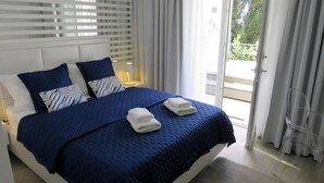 A hotel room with a large bed, two pillows, a blue blanket, and two folded towels. - Villa King (Dubrovnik)