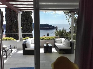 A balcony with a white sofa, a yellow chair, and a small table. - Villa King (Dubrovnik)