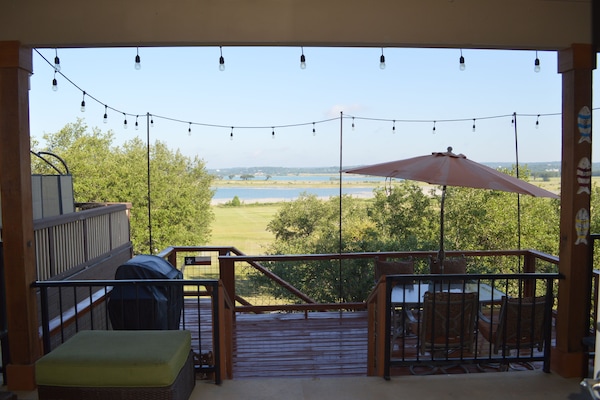 Lake view from porch. Deck just below with table, chairs, gas grill, and lights.