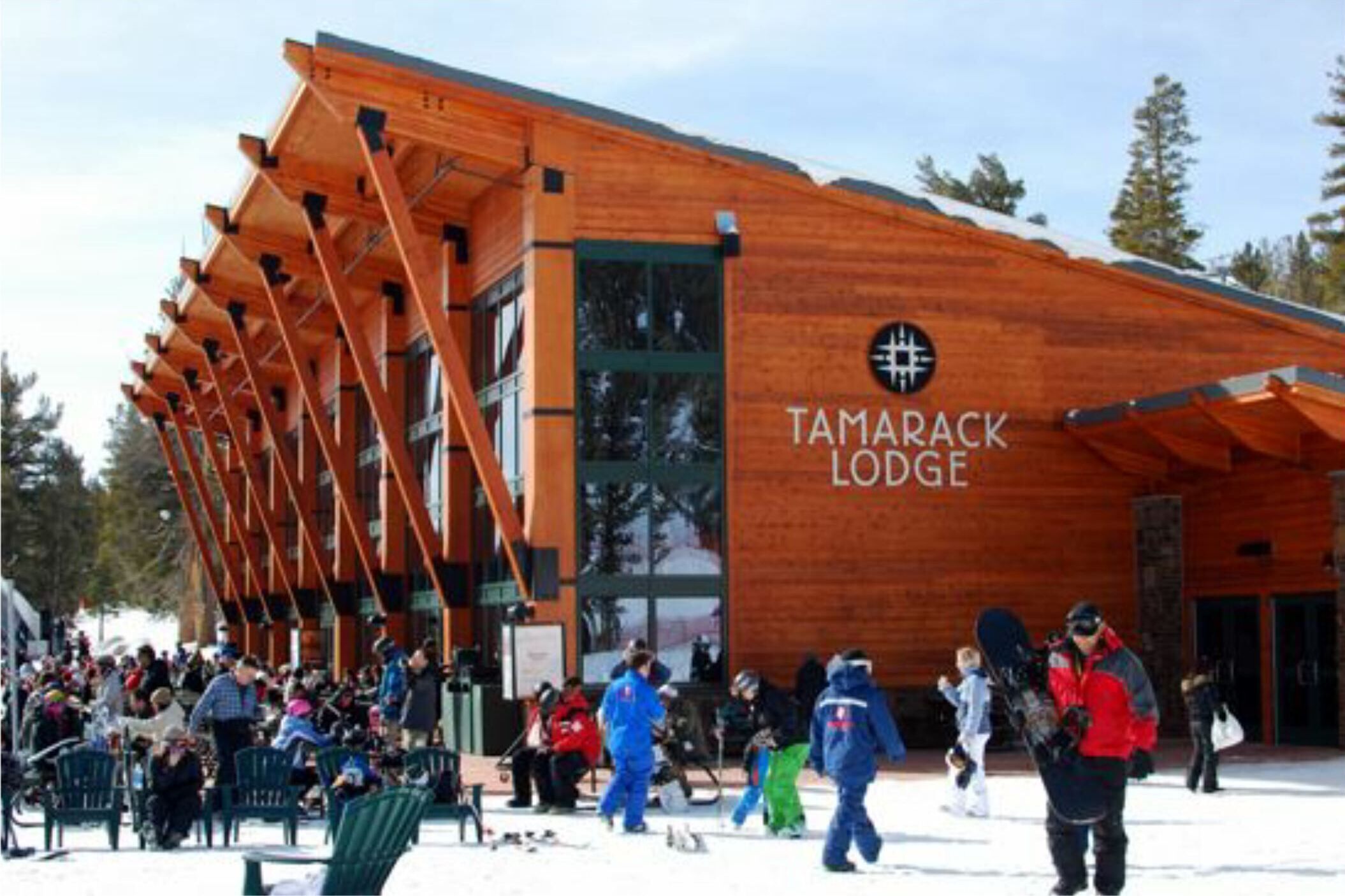 A wooden lodge with a modern design, featuring a large entrance and a sign that reads "Tamarack Lodge".