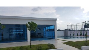 A modern building with large glass windows and a pool area.