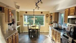 Una cocina con armarios de madera, una mesa de comedor y un ventanal grande.