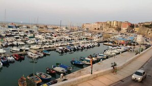 A marina with numerous boats docked, a road adjacent to the water, and buildings in the background. - B&B Agorà Bisceglie (Bisceglie)