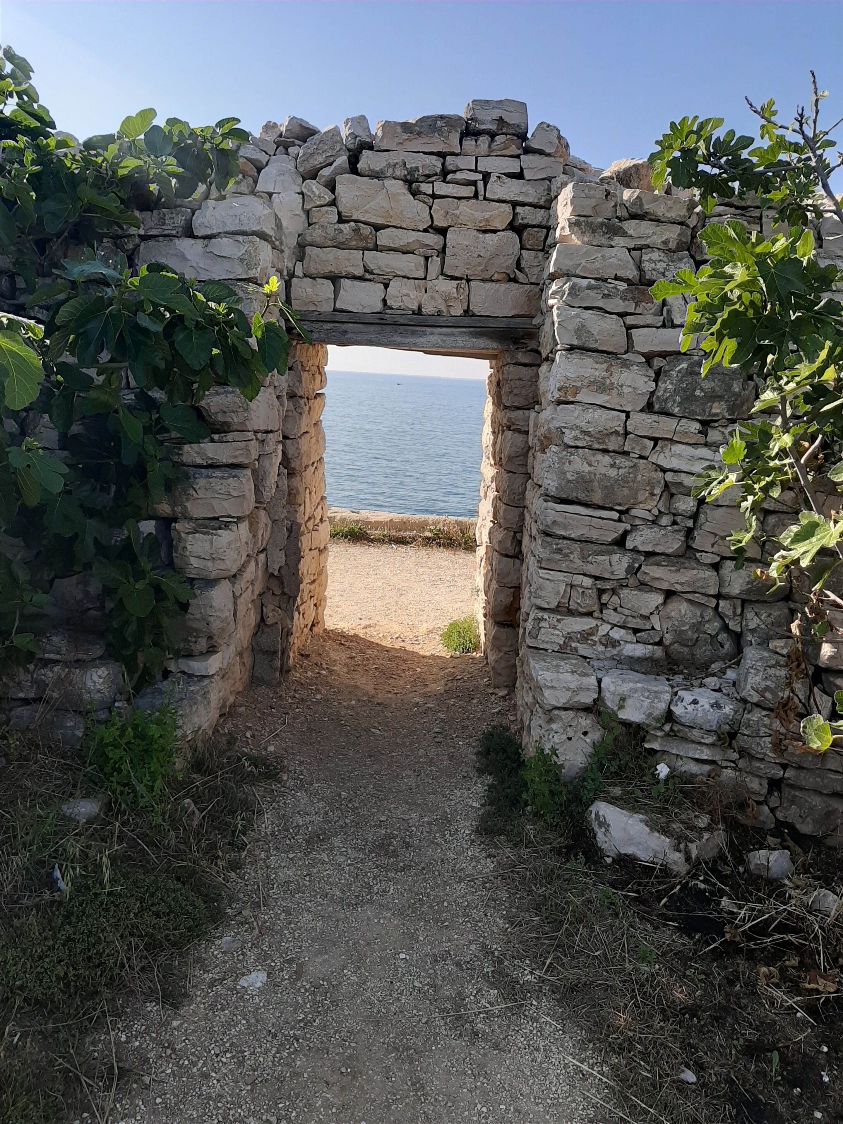 Un arc en pierre menant à une plage.