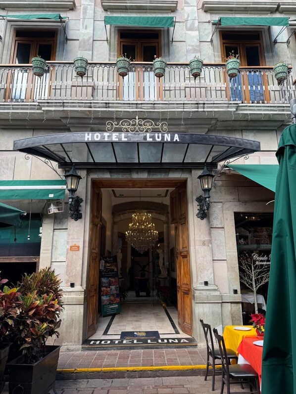 The entrance of Hotel Luna with a grand chandelier, a balcony with hanging planters, and a sign above the entrance. - Hotel Luna (Guanajuato)
