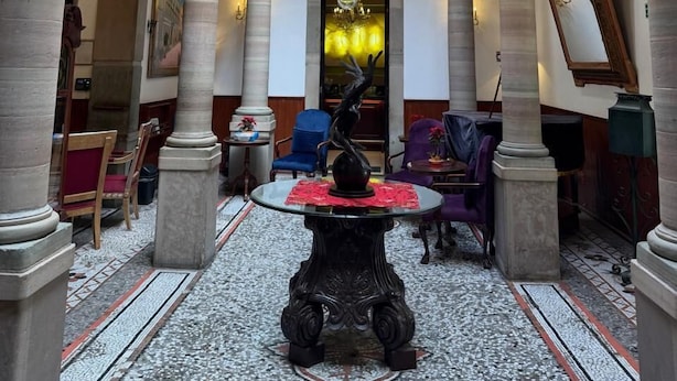 Un amplio vestíbulo con una gran araña, techos altos y arquitectura clásica.