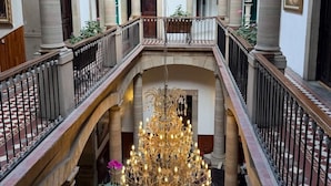 Un amplio atrio con techos altos, un candelabro central y columnas de estilo clásico.