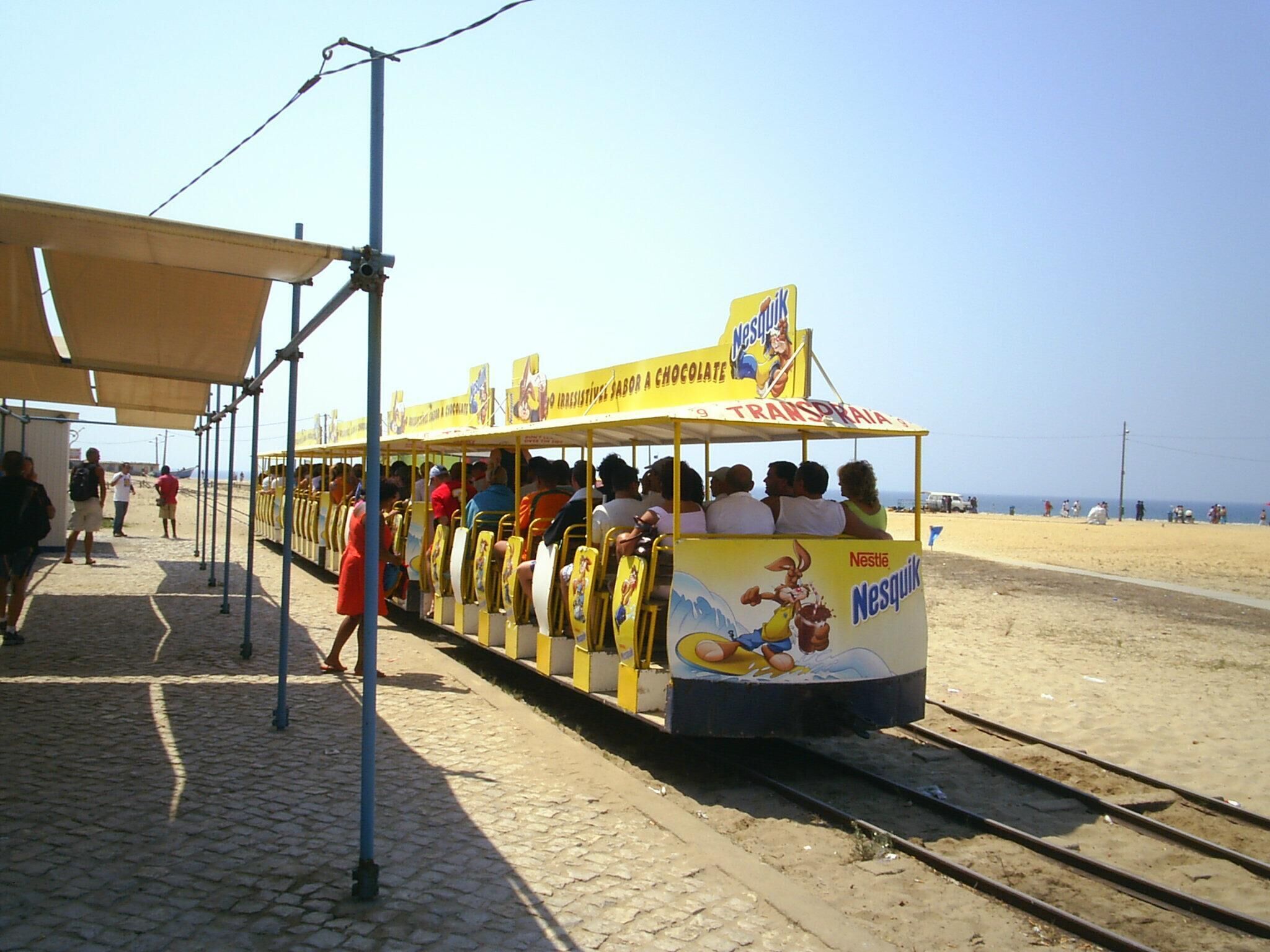 Um elétrico com passageiros em uma linha de trem à beira-mar.