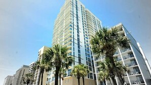A high-rise hotel with multiple balconies and palm trees in front. - ***PRICE DROPS, SPECIAL OFFER AUG 24/30*** Summer Get Away before School (Myrtle Beach)